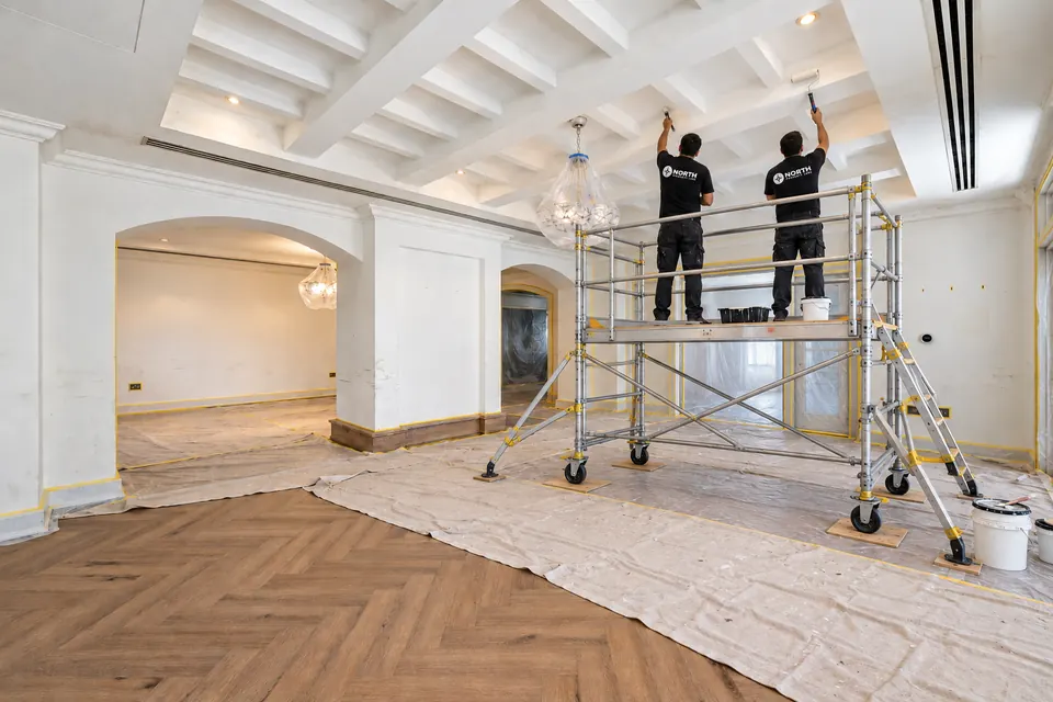 Coffered ceiling being painted with surrounding areas protected