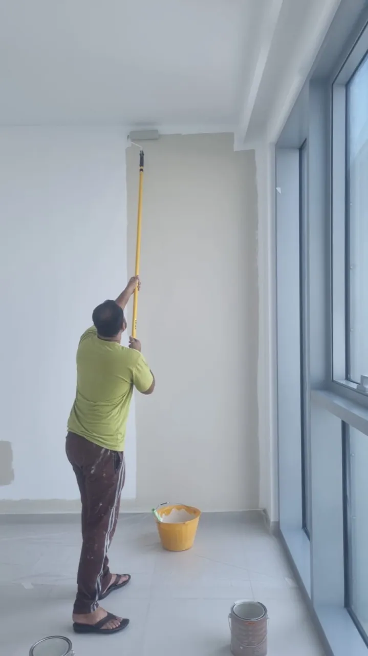 North Property Care painter applying neutral wall paint beside the apartment windows