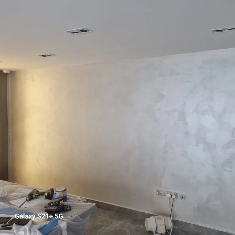 Decorative textured wall finish being applied in the DIFC office, tools on a covered table