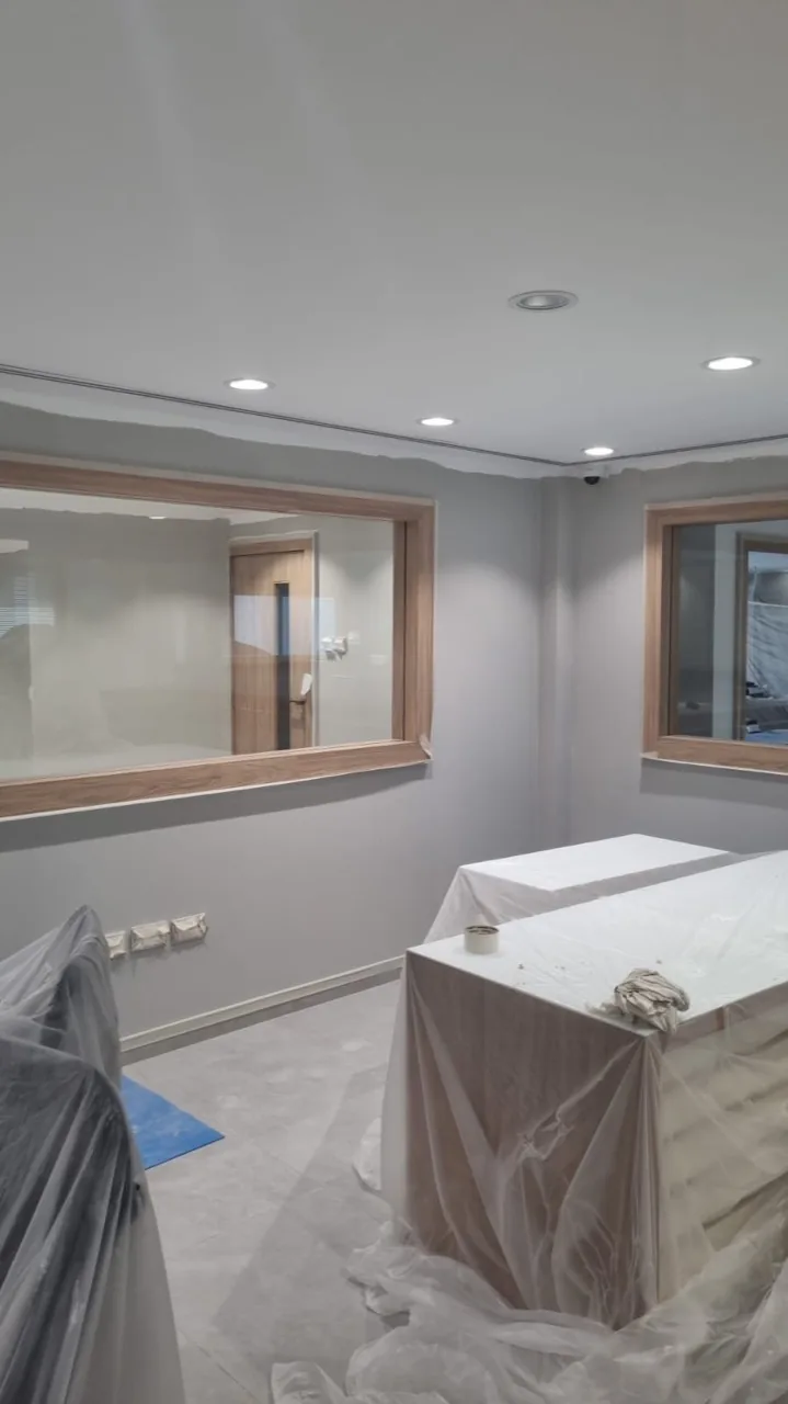 Office room with grey painted walls and furniture covered in protective plastic during painting