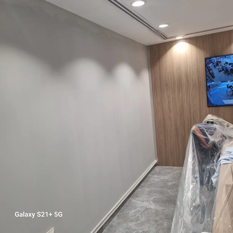 Grey painted office wall beside wood panelling with a protected chair