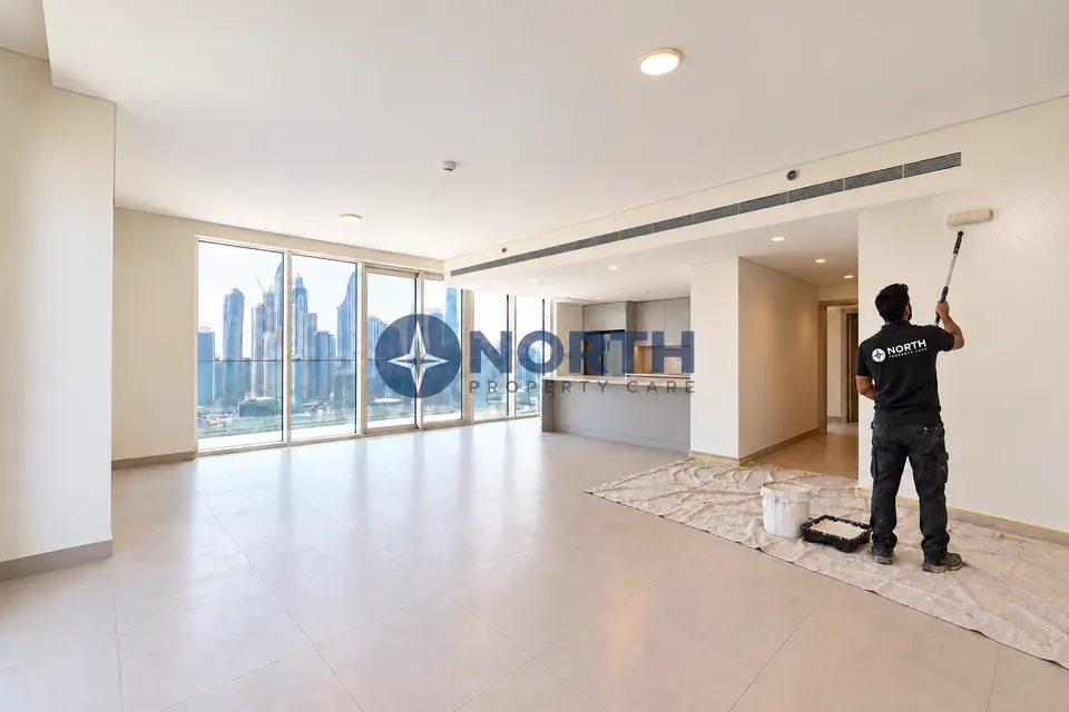 Painter applying paint to a Beach Mansion living-room wall with protective sheets on the floor